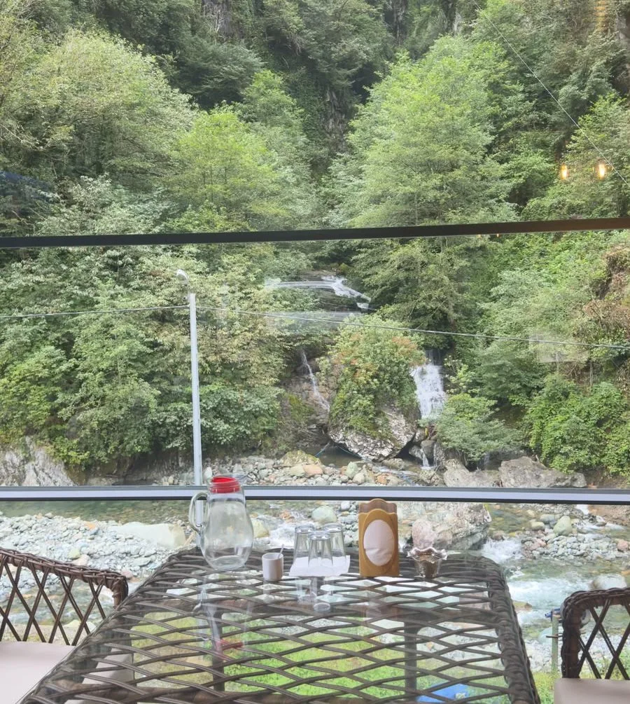 Mençuna Konakları restoranında şelale ve dere manzaralı masa